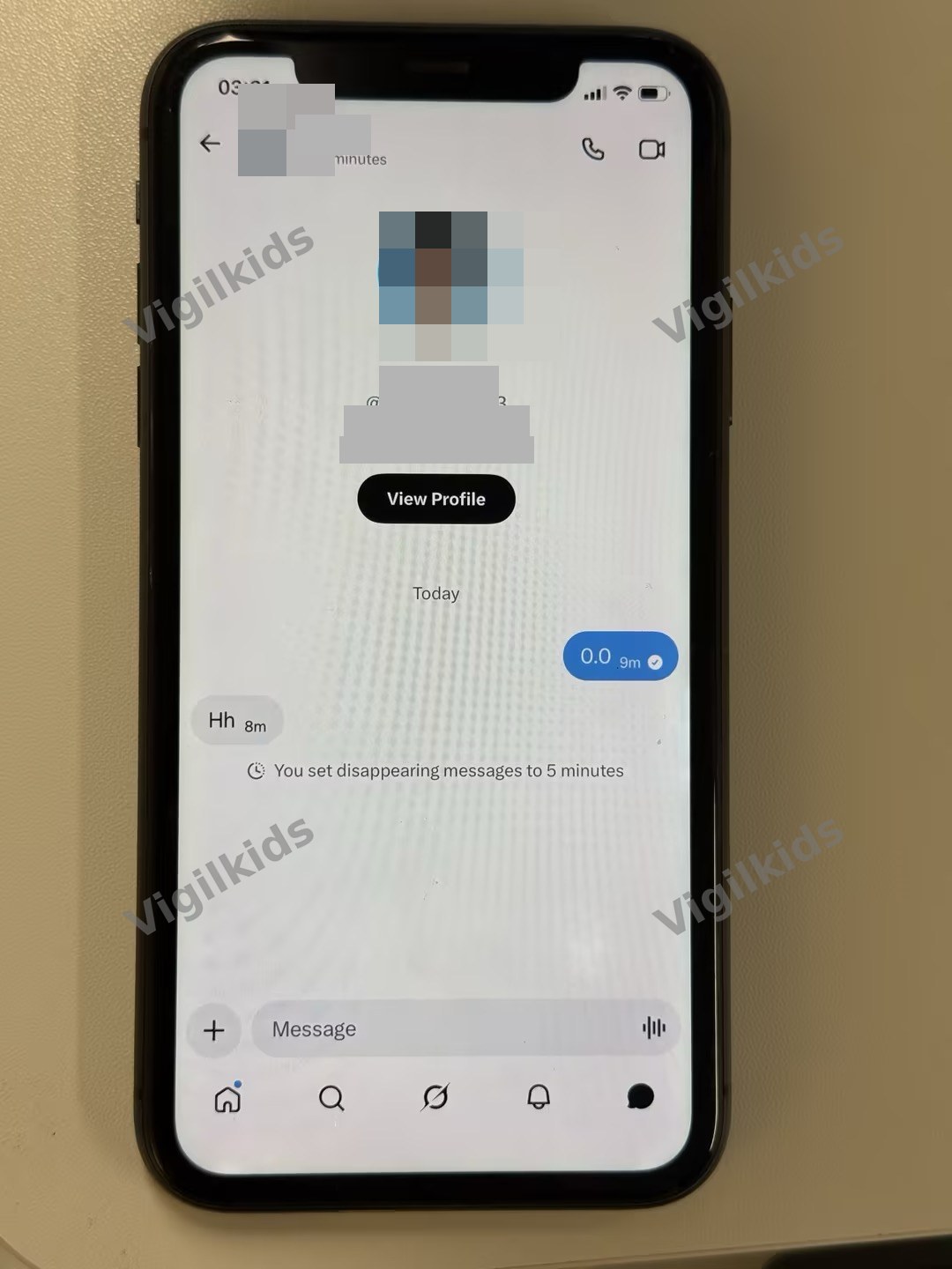 Photo of an iPhone showing an XChat conversation with a 5-minute timer indicator under the contact name and the system note 'You set disappearing messages to 5 minutes' visible inside the chat