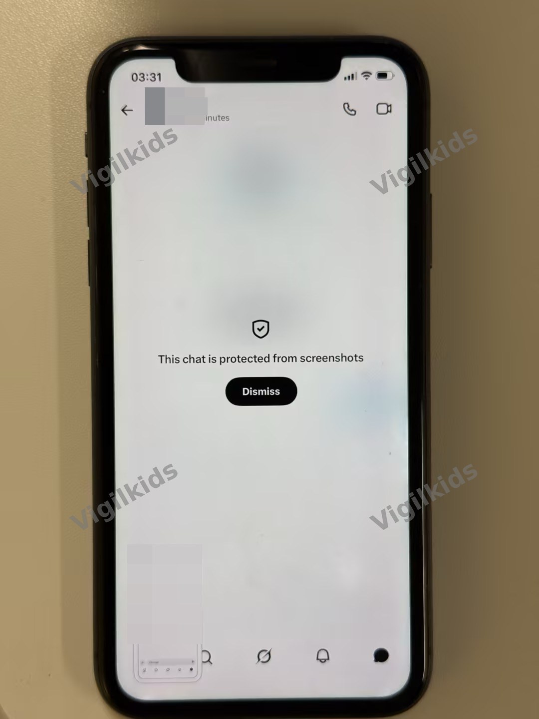 Photo of an iPhone displaying XChat's screenshot-blocked screen with a shield icon, the text 'This chat is protected from screenshots,' and a Dismiss button